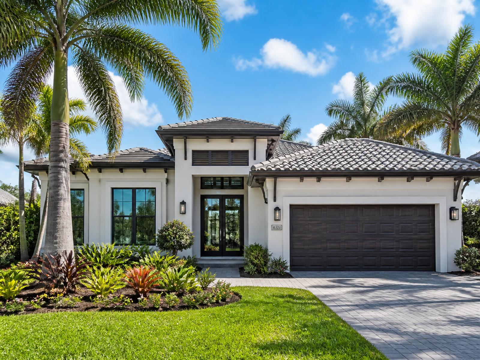 Modern Florida home with a tile roof, palm trees and bright tropical landscaping